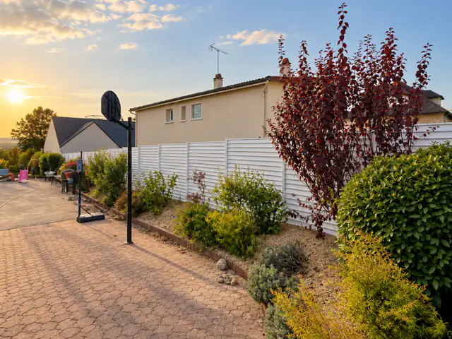Clôture aluminium blanche de 1,86 m posée le long d’un jardin d’Auxerre, massif planté au pied, au soleil couchant
