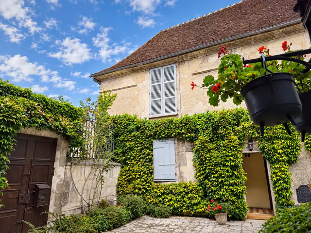 La cour pavée nettoyée, le portail et la porte encadrés de vigne vierge